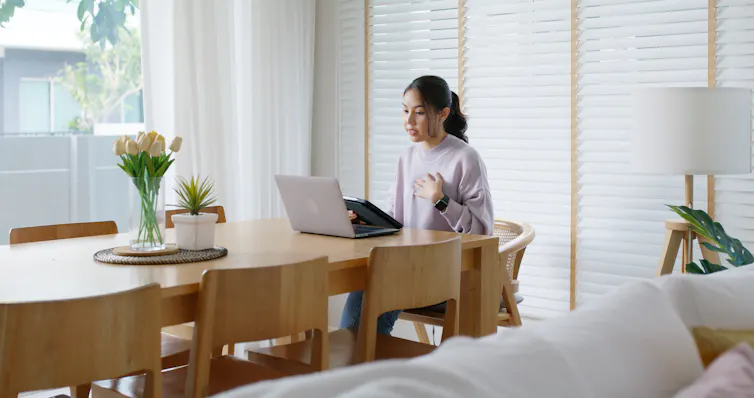 Woman speaks to video call on laptop.