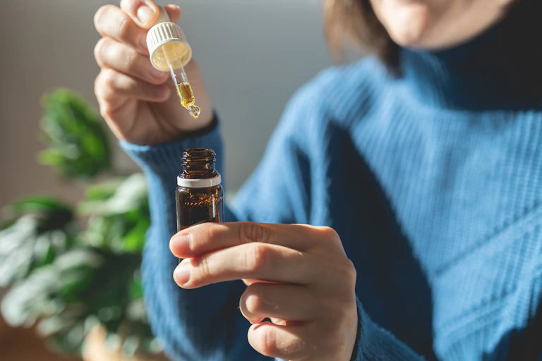 A woman holding a bottle of cannabis oil.
