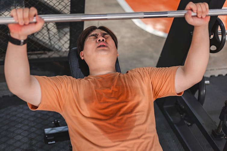 A man sweats while lifting weights
