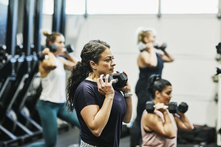 Women lift weights in a class.