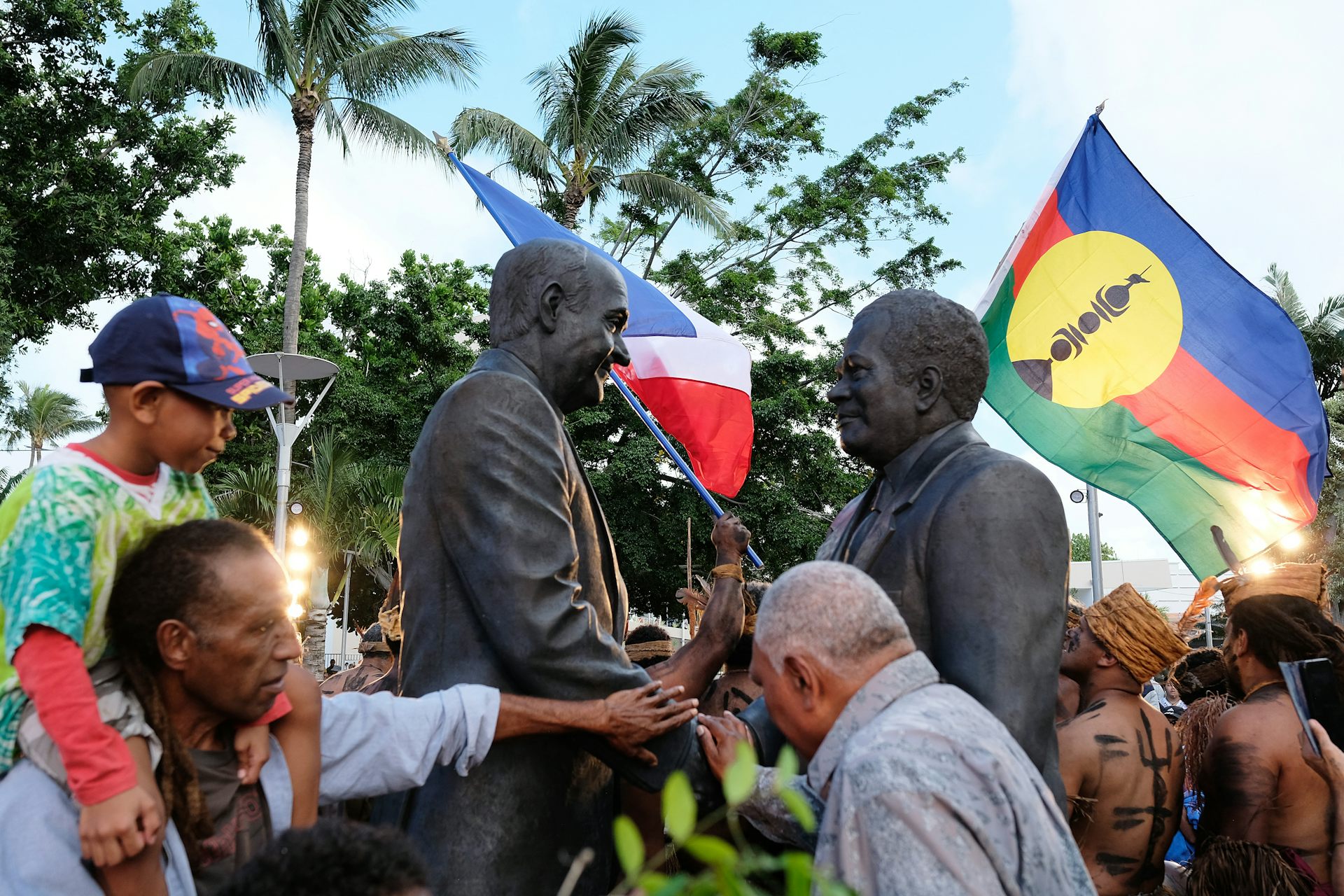 Le public découvre une statue représentant le leader indépendantiste de la Nouvelle-Calédonie Jacques Lafleur (à gauche) serrant la main du leader du mouvement indépendantiste kanak Jean-Marie Tjibaou (à droite) dans le cadre de la signature des accords de Matignon le 26 juin 1988, qui ont apporté la paix à la Nouvelle-Calédonie, lors de son inauguration à Nouméa le 26 juin 2022. La statue de bronze de 2,5 mètres des deux hommes, dévoilée en présence d'hommes politiques et de chefs traditionnels kanak, a été dévoilée au cœur du centre-ville de Nouméa, sur un site aujourd'hui connu sous le nom de « Place de la Paix » ou « Koo Wee Joka » dans une langue kanak locale. (Photo de Theo Rouby / AFP)