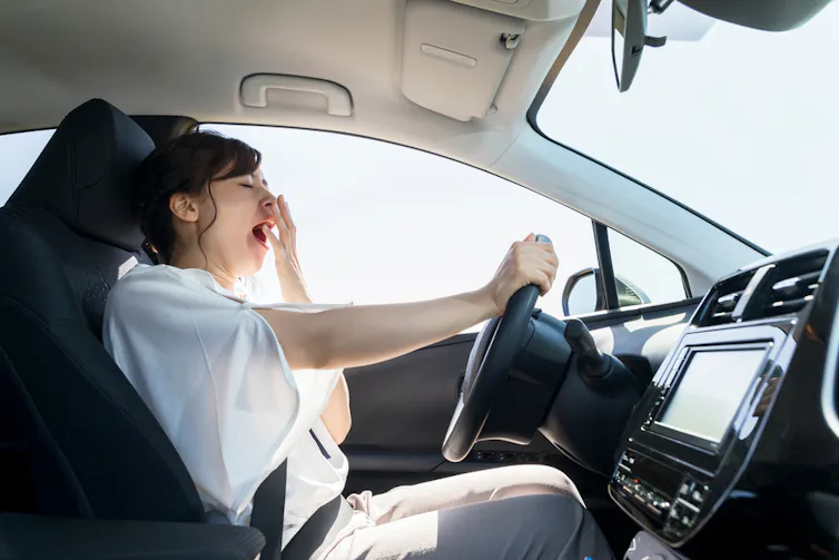 A woman yawning while driving.