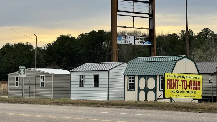 A group of portable sheds for sale on the side of a road.