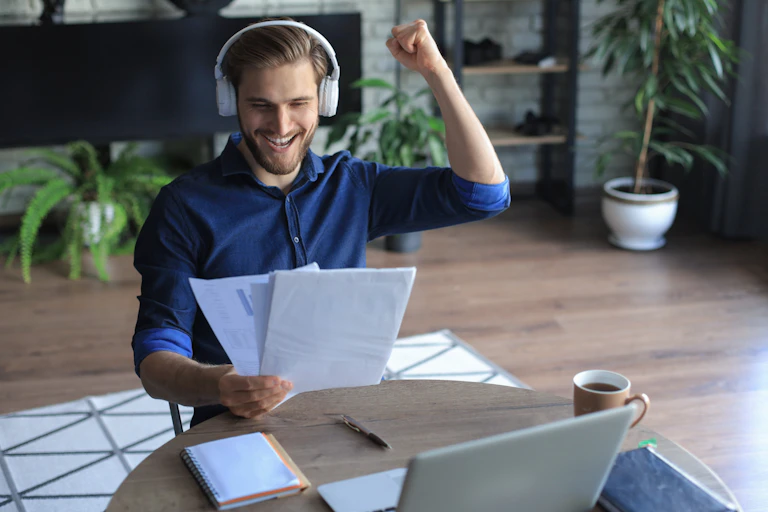 happy male worker sitting at a desk and punching the air