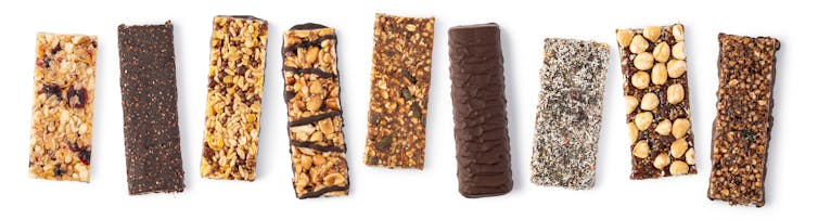 Nine different unwrapped granola bars, some of which have chocolate coating or drizzle.