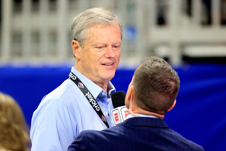 Middle-aged man wearing lanyard being interviewed.