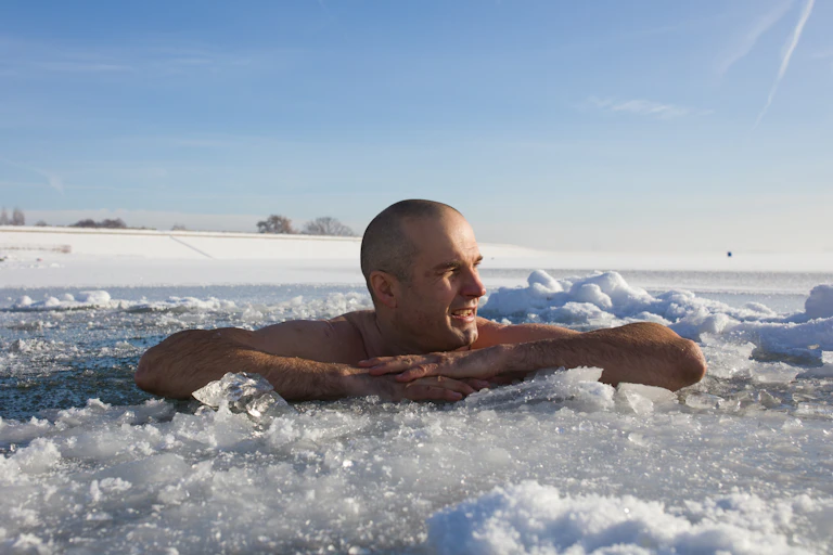 Man taking an ice bath in a frozen lake.