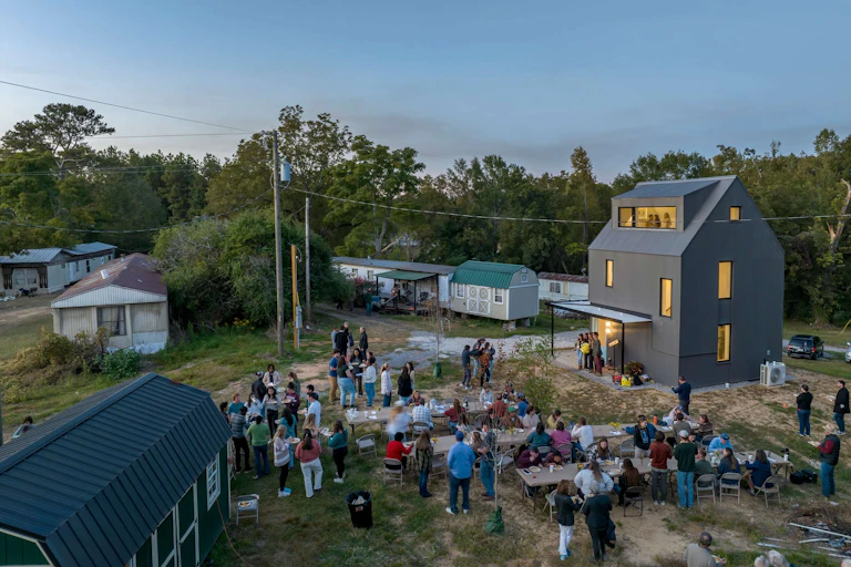 View from a drone of a large gathering on a property with older, existing homes and a brand new home.