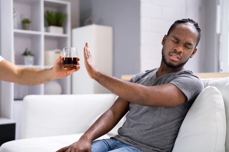 A man refuses an alcoholic drink he is being offered.