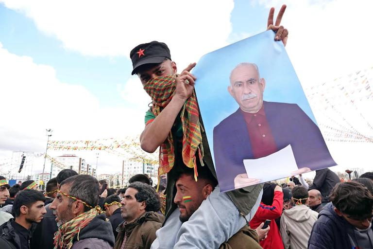 A young man sitting on the shoulders of another man holds up a portrait of PKK leader Abdullah Ocalan in a demonstration in the Turkish city of Diyarbakir