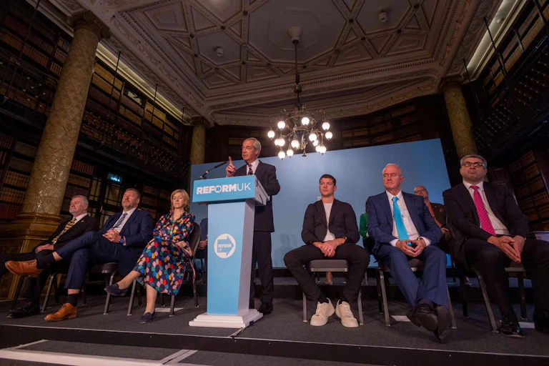 Man at lectern with people sat around him