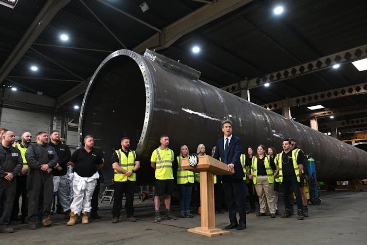 Why wind farm builders are pulling out on the closing minute 2 Ed Miliband at a lectern with a wind turbine component behind him.