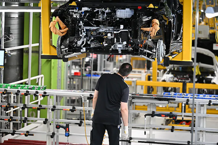 A worker inspects an EV being manufactured.