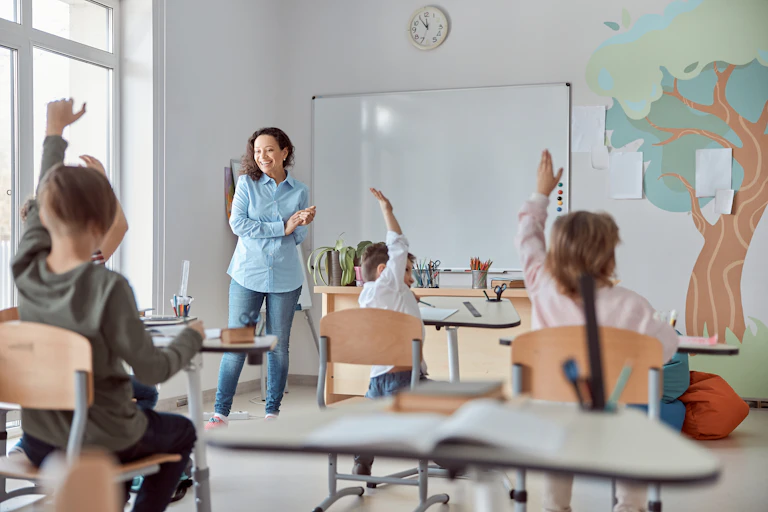 Varios niños levantan la mano en una clase.