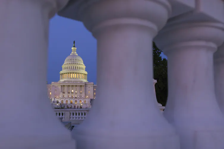 A view of the U.S. Capitol building through the pillars of a nearby railing.