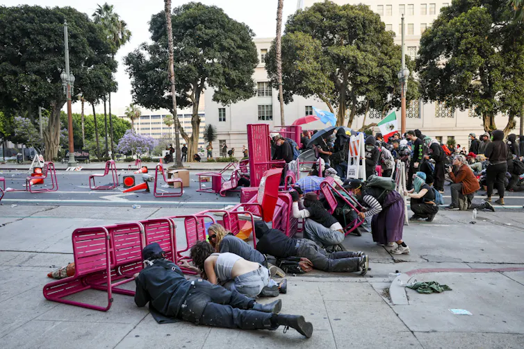 Protesters crouch behind a row of overturned furniture on a street.