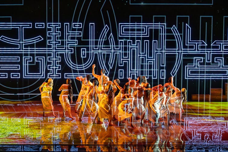 The dancers in front of abstract symbols.