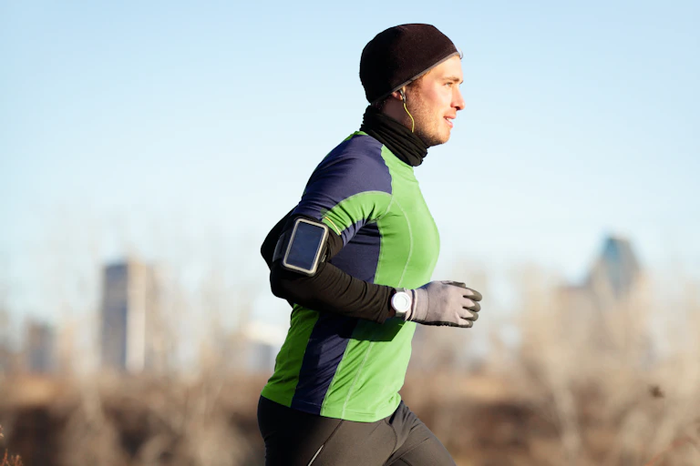 A man runs wearing layers, gloves and a beanie;