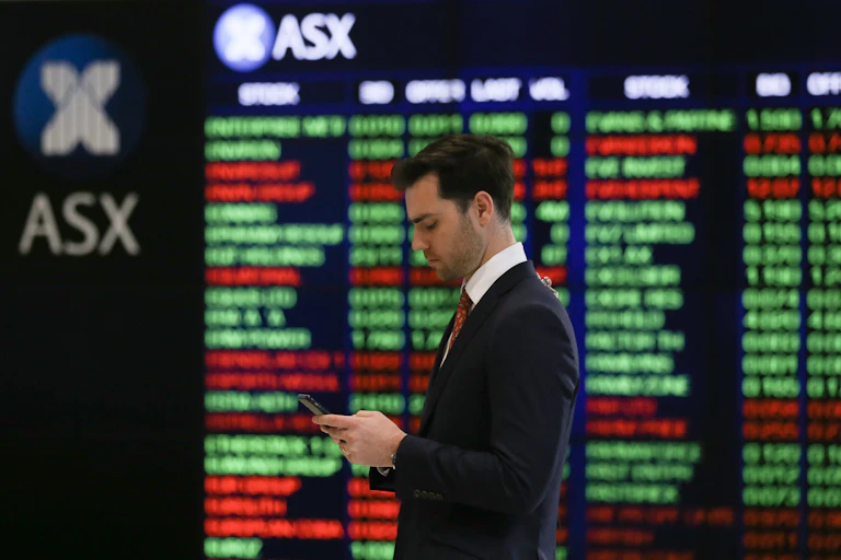 Man standing in front of stocks board at stock exchange