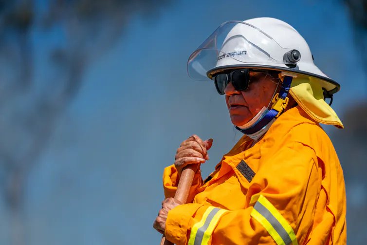 A person in orange clothes holding a tool.