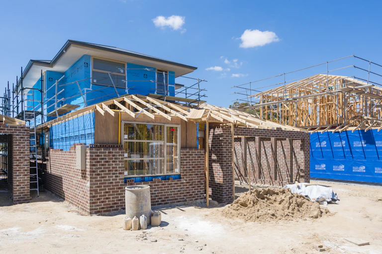 Two half built homes set against a blue sky