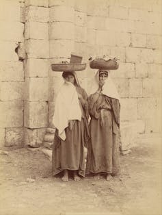 Fotografía de dos mujeres con cestos en la cabeza.