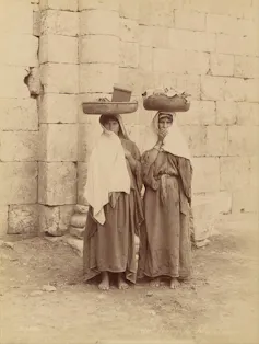 Fotografía de dos mujeres con cestos en la cabeza.