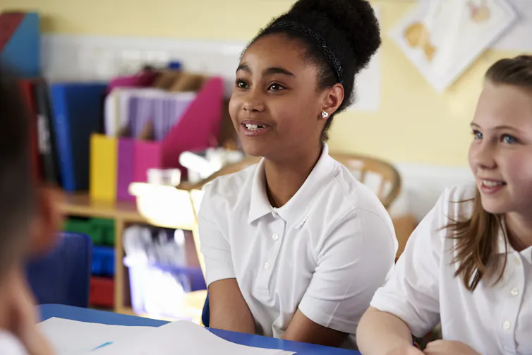 two primary-aged schoolgirls sitting at their desks.