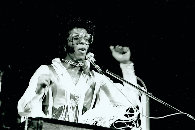 The black fun pioneer Sly Stone dressed in white on stage at Woodstock in 1969.