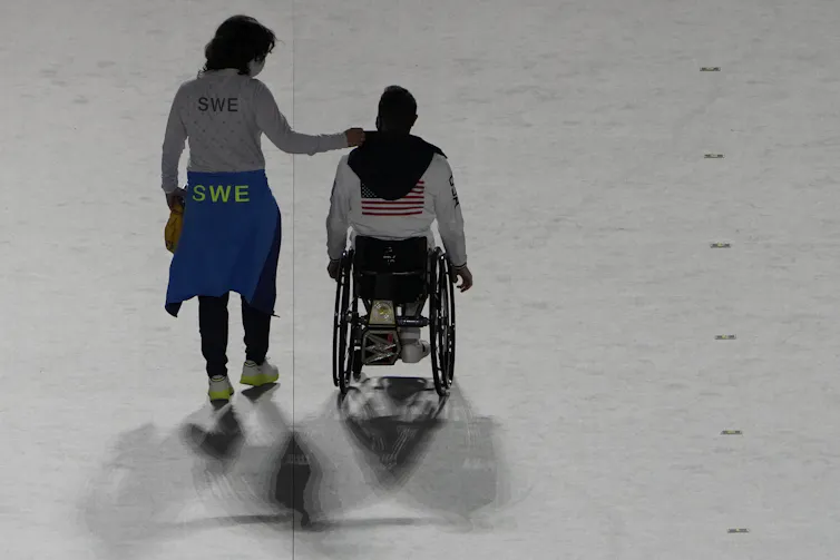 Une personne marche et l’autre se déplace en fauteuil roulant