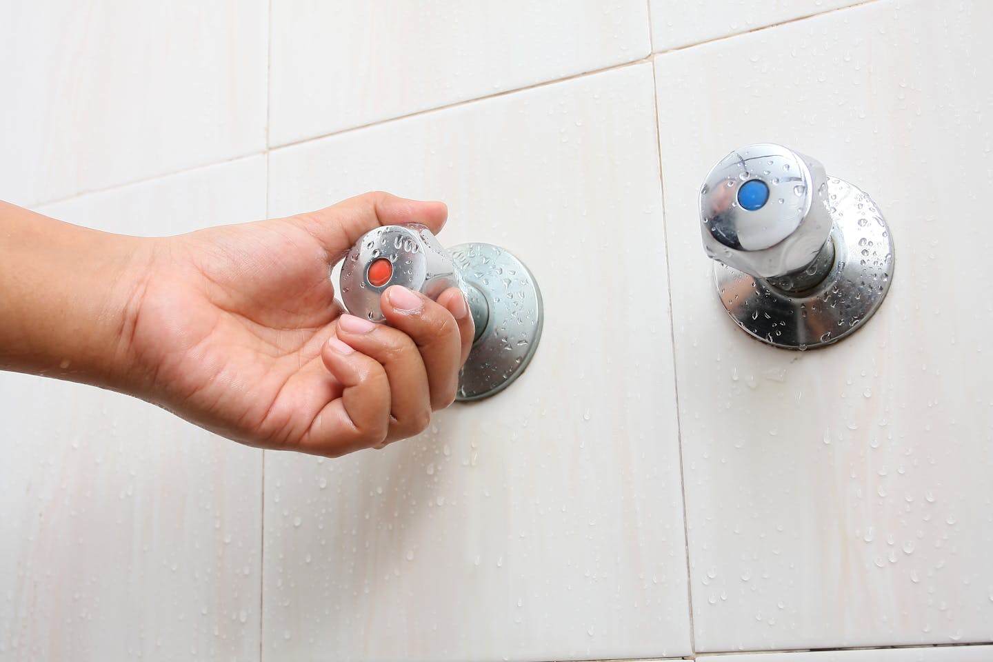 Stock photo of a hand turning on a hot water faucet in bathroom