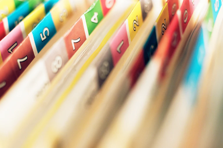 Close-up of manila folders with color-coded numbered stickers on their sides
