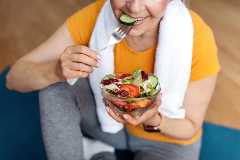 Une femme mange de la salade.
