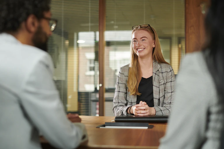 Young woman across the table from two interviewers.