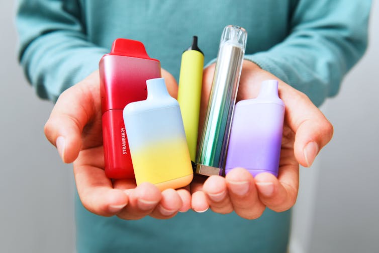 School-aged kid displaying a variety of vape cartridges.