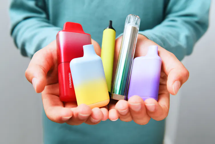 School-aged kid displaying a variety of vape cartridges.