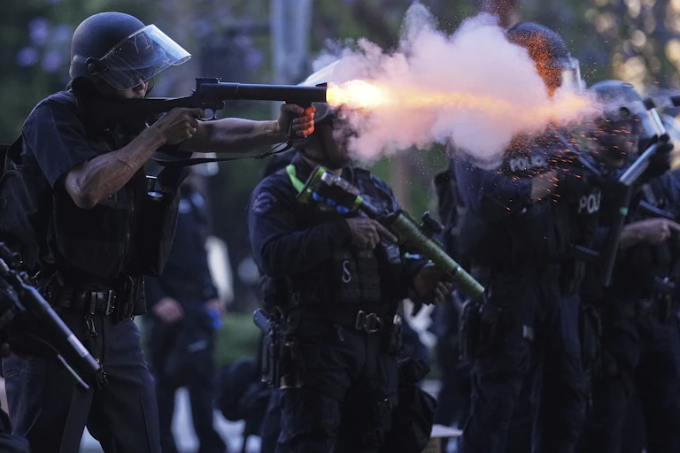 A police officer fires a 'less lethal' round in downtown Los Angeles.