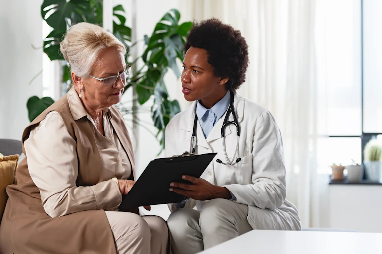 A doctor in a white coat consulting with an older woman