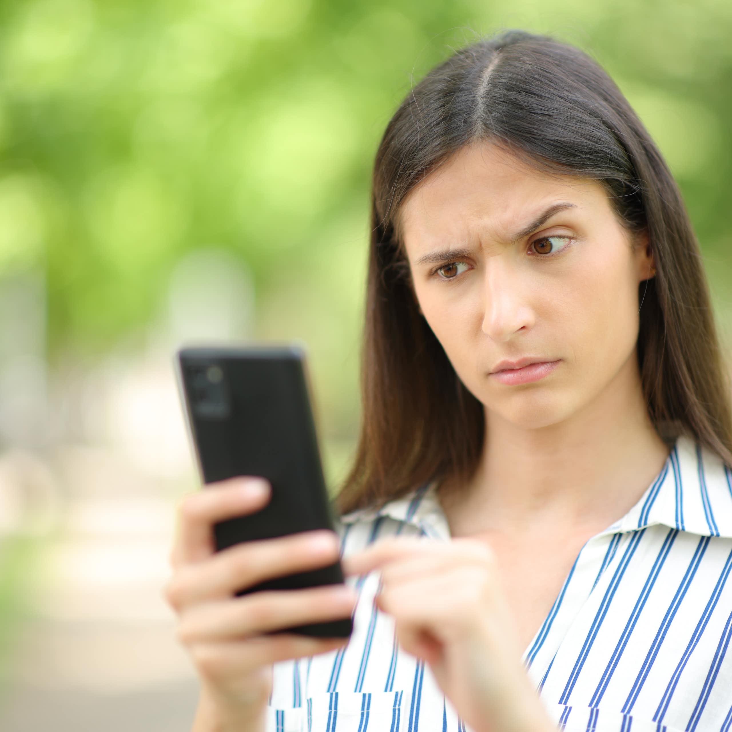 Una chica levanta una ceja ante lo que ve en su móvil