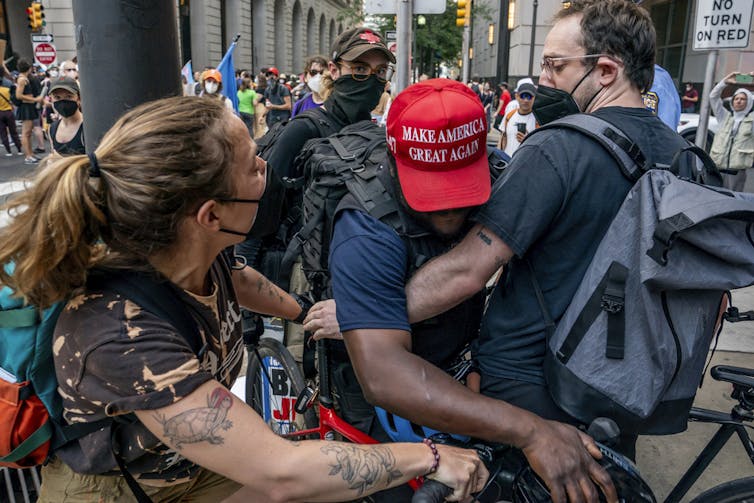 A man struggles through a crowd of protesters.