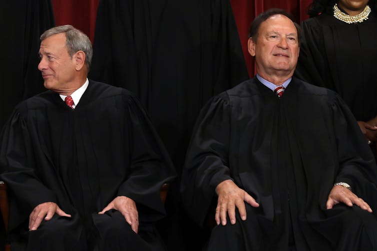 Two men in black robes sitting next to each other.