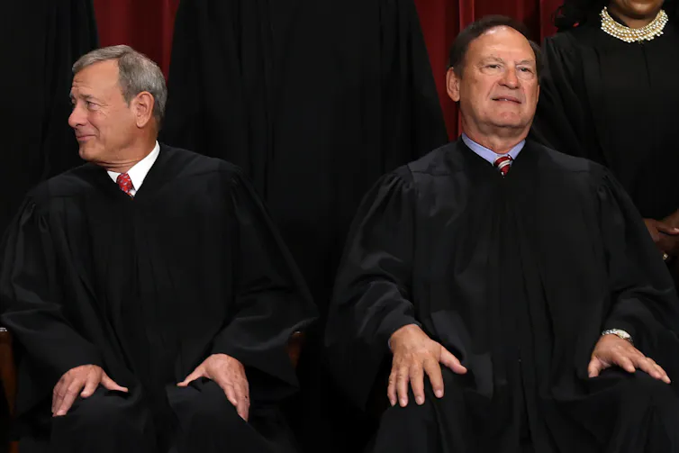 Two men in black robes sitting next to each other.