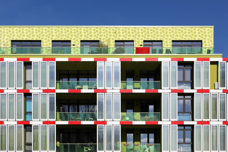 Un edificio verde con balcones que tiene una fachada de microalgas