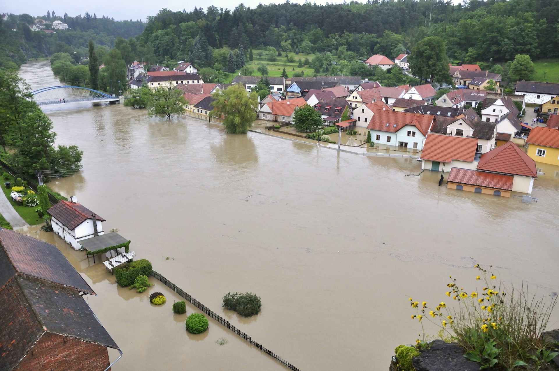 A river with brown water has partially flooded some nearby buildings.