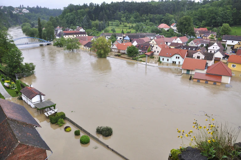 A river with brown water has partially flooded some nearby buildings.