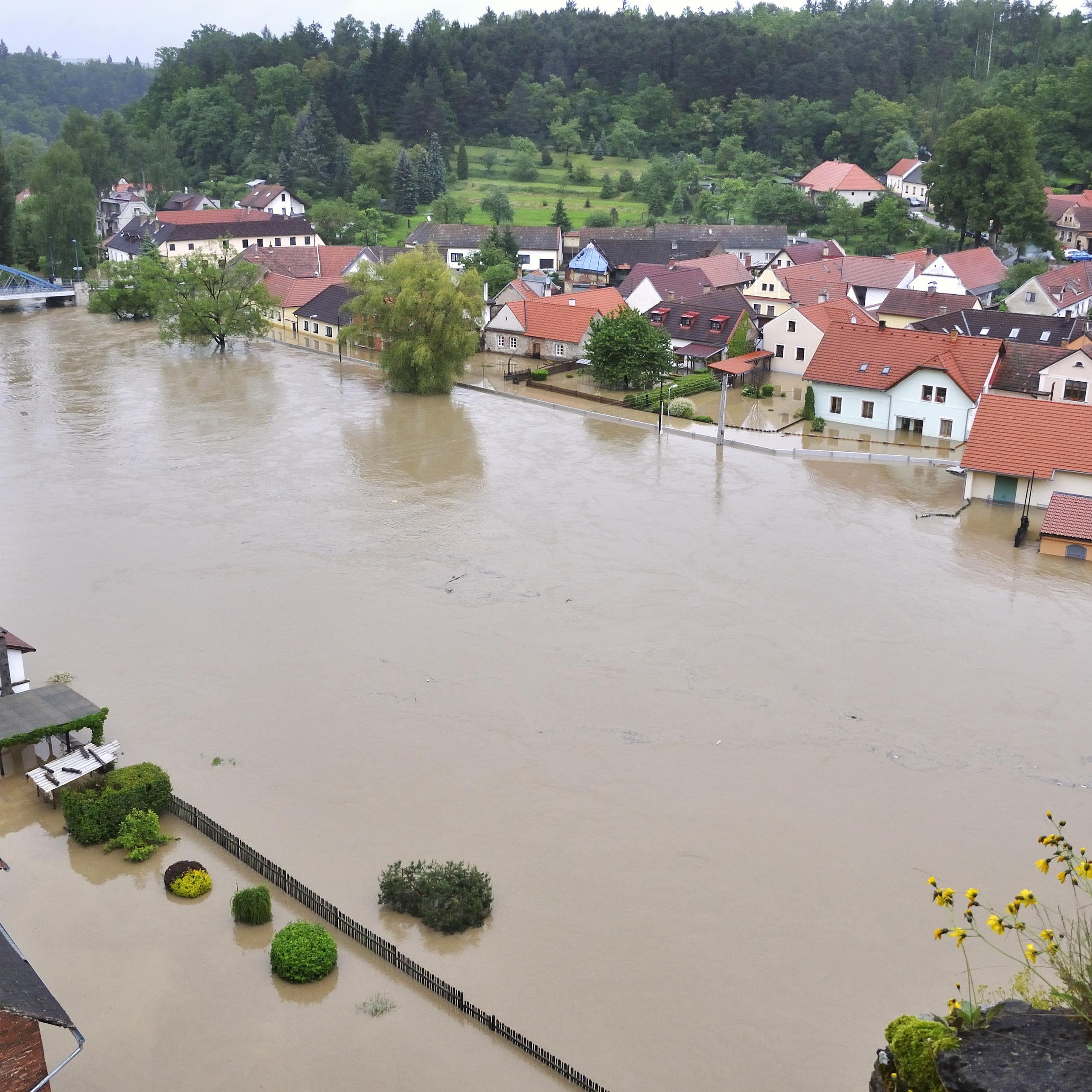 A river with brown water has partially flooded some nearby buildings.