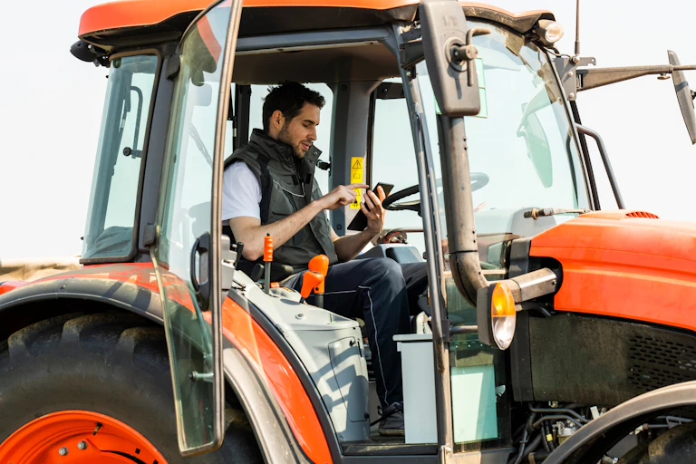Un homme dans un tracteur avec un smartphone à la main