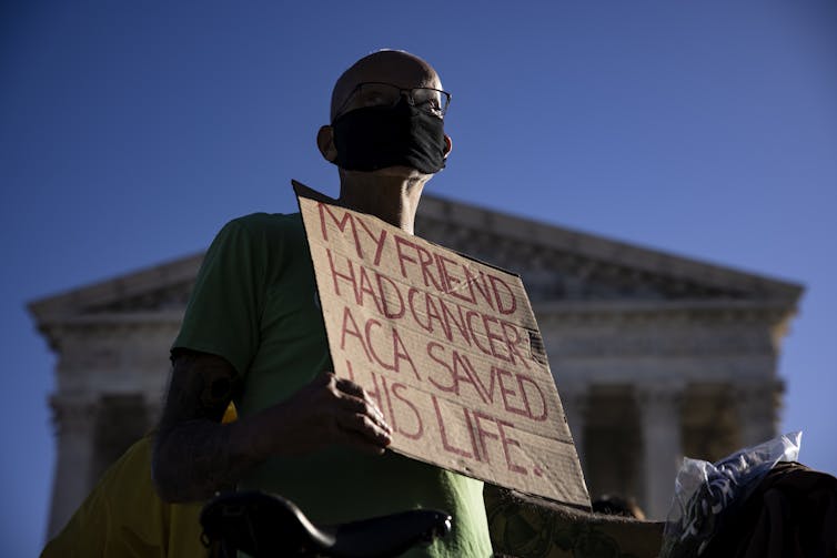 Protester holds sign that says 'My friend had cancer. ACA saved his life.'