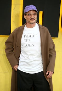 Actor Pedro Pascal wears the 'Protect the Dolls' shirt with a brown coat.