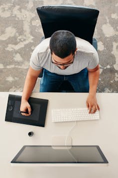 A graphic designer, seen from above working at a desk